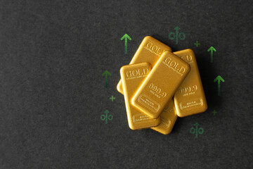 Top view of gold bars on a dark background with green arrows and percentage signs. Concept of...