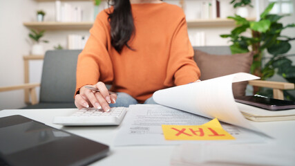 Tax preparation. Woman calculating taxes at home office with documents and calculator.