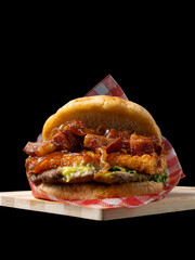 Artisan Colombian Burger with Beef Patty, Crispy Chicharrón (Pork Belly), Avocado Sauce, and Caramelized Onions, Isolated on Black Background