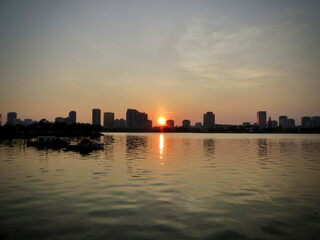 Symmetry at Sunset: City Skyline Reflected on Still Water on West Lake in Hanoi, Vietnam