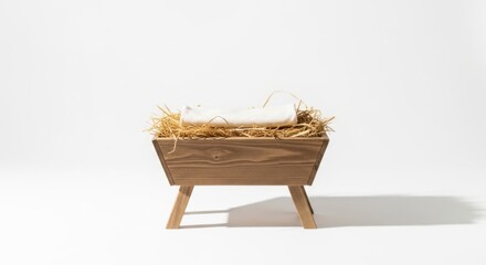 Minimalist wooden manger with hay and a small white cloth on a clean white background