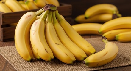 A bunch of ripe yellow bananas in a wooden crate with more bananas in the background