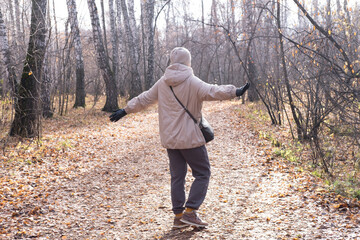 Happy, smiling 40-year-old woman enjoys the warm, sunny weather in an autumn park. Hello, autumn!