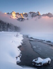 Snowy river landscape with mountains partially veiled in mist