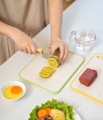 Woman Slicing Lime on Green Cutting Board Next to Yellow Board with Beef and Vegetables on White Table Stock Image