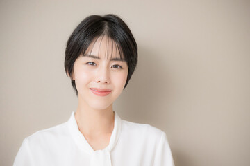 ベージュ背景でカメラ目線の笑顔の女性のクローズアップ