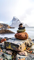 Stone cairn balances near a snowy mountain and ocean