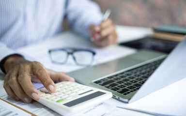 accountant working with laptop on desk in office checking financial documents calculate business costs, profits and tax