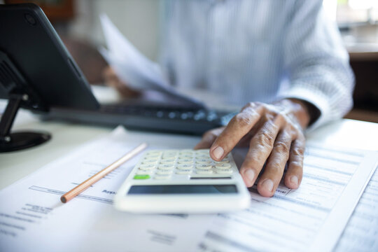 close up shot, accountant calculate business costs, profits and tax working with tablet on desk in office checking financial documents - Powered by Adobe