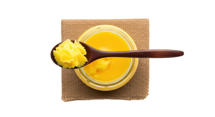 Wooden spoon with fresh yellow ghee in glass jar on rustic mat top view