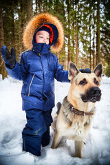 Child and dog enjoying winter playtime in snowy forest with trees in background