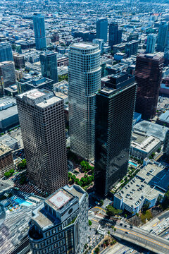 Aerial view of downtown Los Angeles California skyline with modern glass skyscrapers, hotels, and Crypto.com Arena under clear summer sky showing vibrant city growth