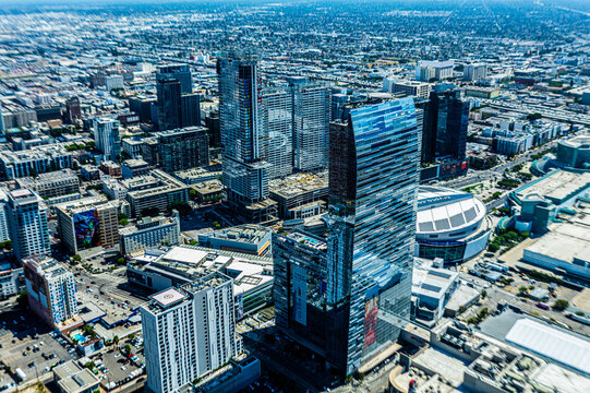 Aerial view of downtown Los Angeles California skyline with modern glass skyscrapers, hotels, and Crypto.com Arena under clear summer sky showing vibrant city growth