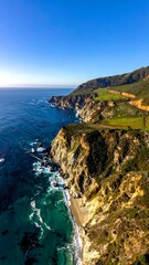 Coastal landscape showcases cliffs, ocean, beach, and blue sky