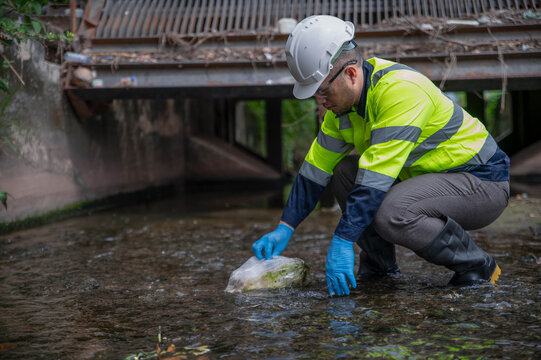 An environmental expert is collecting trash to make the stream water cleaner and flow more smoothly. - Powered by Adobe