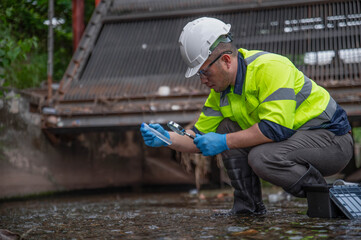 A specialist biologist is examining the water in a stream to detect microscopic organisms in the water to determine the health of the stream's ecosystem.