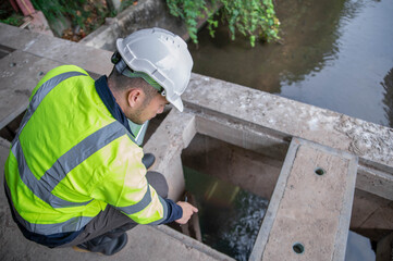A specialist engineer is examining contaminants in water that has been scooped out of waste.