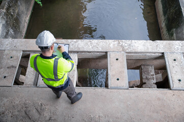 A specialist engineer is examining contaminants in water that has been scooped out of waste.