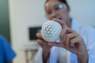 Researchers are working with a 3D printer to print clear, white plastic models using cutting-edge,...