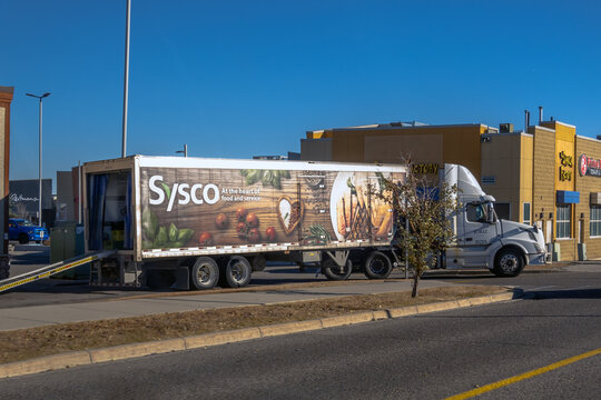 Calgary, Alberta, Canada. Oct 29, 2025. A Sysco food service delivery truck, with a vibrant food-themed graphic on its trailer, parked in an urban commercial area.