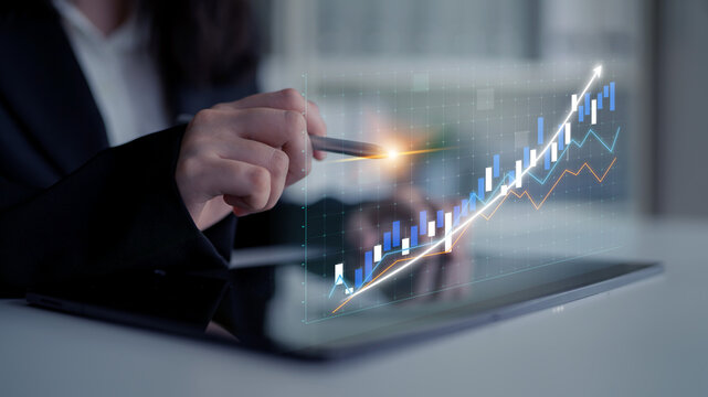 A professional individual analyzes data on a tablet, showcasing digital graphs and charts that represent growth and financial performance in a modern workspace. Impute