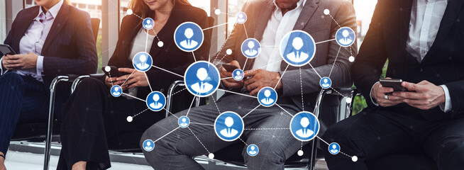 A group of professionals in business attire waiting in a modern office setting, each engaged with their smartphones, surrounded by social network connection graphics. Tessel