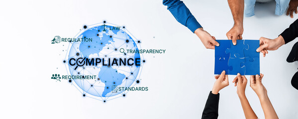 Hands work together to connect puzzle pieces on a global compliance theme. Elements of law,...