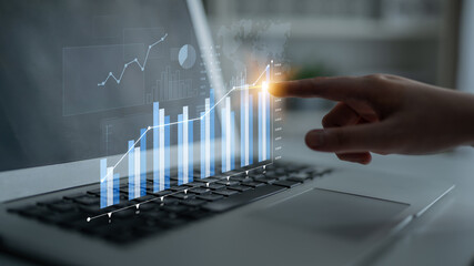 A focused view of a modern laptop displaying data analytics with a finger pointing at a growth...