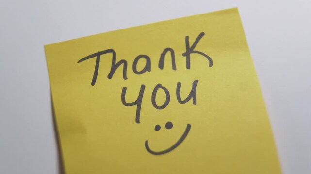 Person sticking thank you note on a white surface