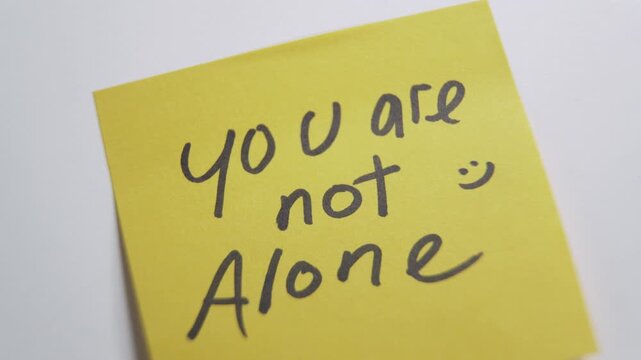 Hand sticking a you are not alone note. mental health