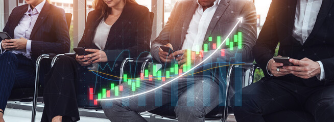 Business professionals in suits using smartphones while sitting in a modern office with financial...