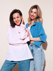 Two young beautiful smiling female in trendy summer clothes. Carefree women posing in studio....