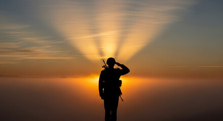 Silhouette of a soldier saluting during sunset or sunrise with sun rays.
