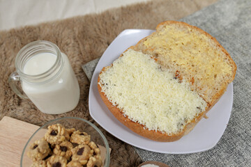 Bread with cheese, sweetened condensed milk, and butter. With white milk and snack on a table for breakfast	
