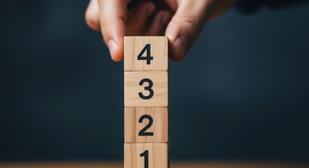 Hand placing a wooden block with the number four on top of a stack of blocks