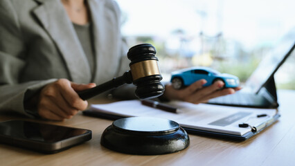 A lawyer signing a car contract with a gavel and a toy car on the desk, symbolizing car law, insurance, or legal agreement.