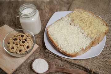 Bread with cheese, sweetened condensed milk, and butter. With white milk and snack on a table for breakfast	
