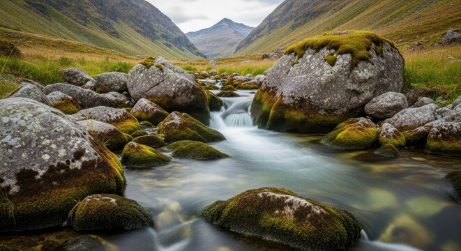 Discover the tranquil beauty of Scotland's Glen Etive with a stunning river flowing through mossy rocks, framed by majestic mountains under a soft, serene sky perfect for travel blogs
