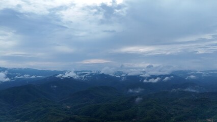 Fototapeta premium Green mountain valley landscape in Kunming,Mountains and clouds in Kunming, Yunnan,Natural mountain scenery in Kunming,Kunming valley surrounded by green hills,Misty mountain forest in Kunming