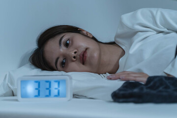 Young woman sleepless during night time on the bed.