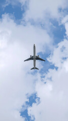 Fototapeta premium Airplane ascending through fluffy white clouds against a bright blue sky