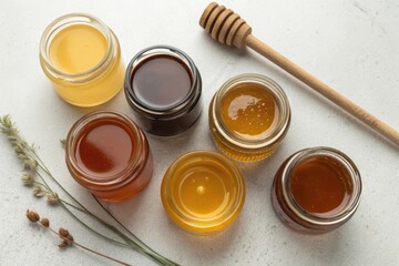 Variety of Honey Jars with Honey Dipper and Fresh Herbs on Table