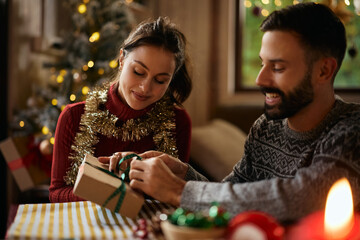 Smiling woman wrapping Christmas gifts with her boyfriend at home.