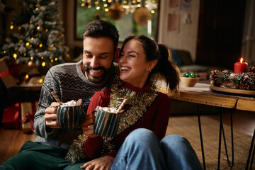 Joyful couple drinking hot chocolate on Christmas day at home.