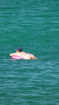 Woman, floating, sea, enjoying serene summer vacation leisure on inflatable in turquoise water. Vertical video