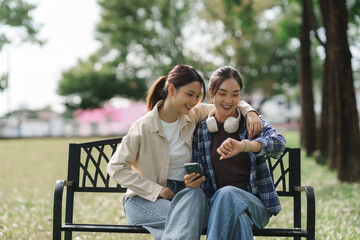 Young women sharing smartphone and smartwatch in park