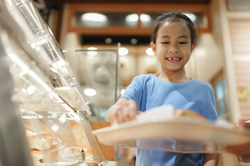 Happy young girl selecting bakery breakfast