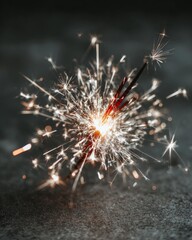 Fototapeta premium Bright Sparkler Burning on Dark Surface