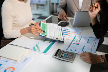 Business team analyzing documents, graphs, and data with a laptop, tablet, and smartphone. Collaboration, strategy, and success.