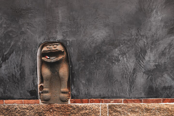 Wind Lion God of Kinmen embedded in wall to prevent bad luck. Copy space, grey wall background.